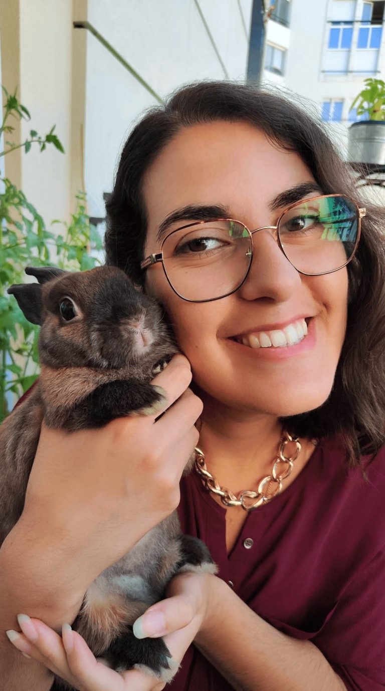 Pauline Fontaine-Doerr Femme souriante tenant un lapin dans ses bras, entourée de plantes.